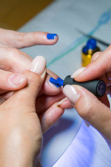 Beautiful manicure process. Nail polish being applied to hand, polish is a blue color. closeup. vertical photo