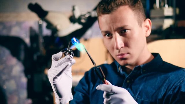 Male silversmith is burning the frame of the silver ring. Jeweler makes a piece of jewelry