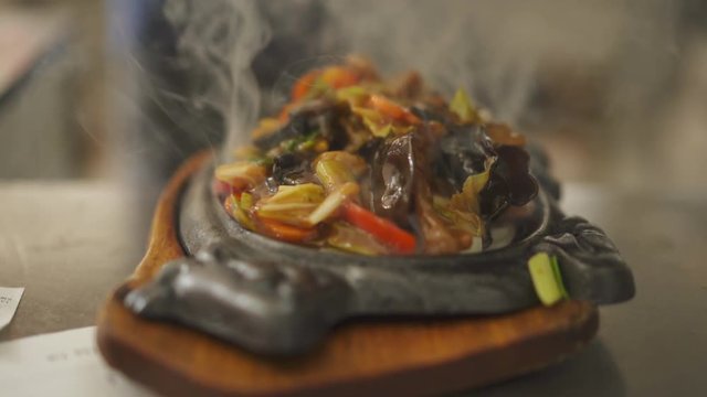 Close up view of a smoky fresh cooked dish arranging into Cast-Iron Sizzler Plate.