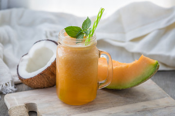 Photo of melon smoothie in jar with straw on light background. Fresh organic Smoothie. Health or detox diet food concept. - obrazy, fototapety, plakaty