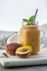 Photo of peach smoothie in jar with straw on light background. Fresh organic Smoothie. Health or detox diet food concept.