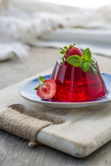 Photo of summer Jelly Dessert with strawberry. Garnished with a sprig of fresh basil on light background. - 280786144