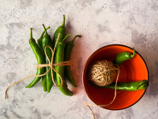 A few green hot peppers shot from above on a light stone background. Plenty of space for text.