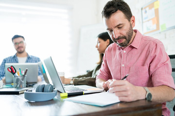 Male Executive Writing Ideas On Paper At Office