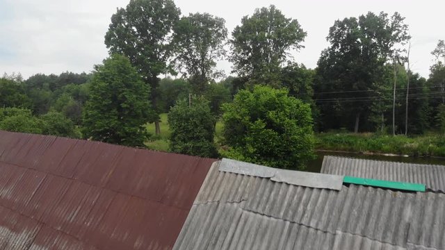 Fly close along a wide road in the village. Flying over the forest and the road. Unmanned view. Harvest, agriculture concept. Houses of old people in the village