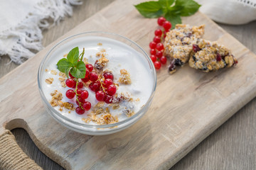 Bowl of fresh red currant and yogurt. Photo of breakfast bowl with farm fresh currant served on a wooden board.