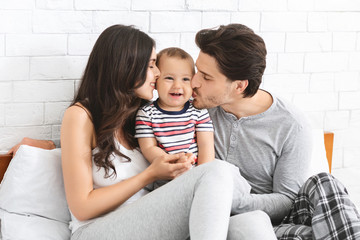 Young loving parents kissing their adorable baby son