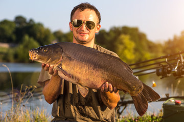 Happy angler with carp fishing trophy