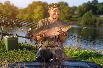Happy angler with carp fishing trophy