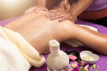 Massage and body care. Young woman tan or honey skin receiving relaxing shoulder massaging in a spa house. Beautiful woman having massage in the spa salon for beauty care.