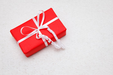 Red gift box with white ribbon on white background