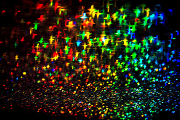 Multicolor neon lights star flares and rainbow glitter on isolated black background. Bokeh lens...