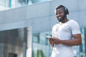Portrait of african man in headphones with cellphone outdoor