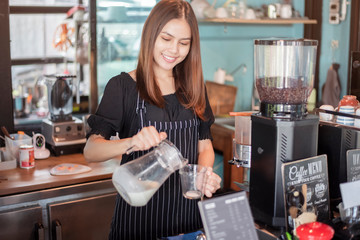 Beautiful barista is smiling  in her coffee shop