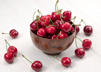 .sweet cherries in a plate on a wooden white background