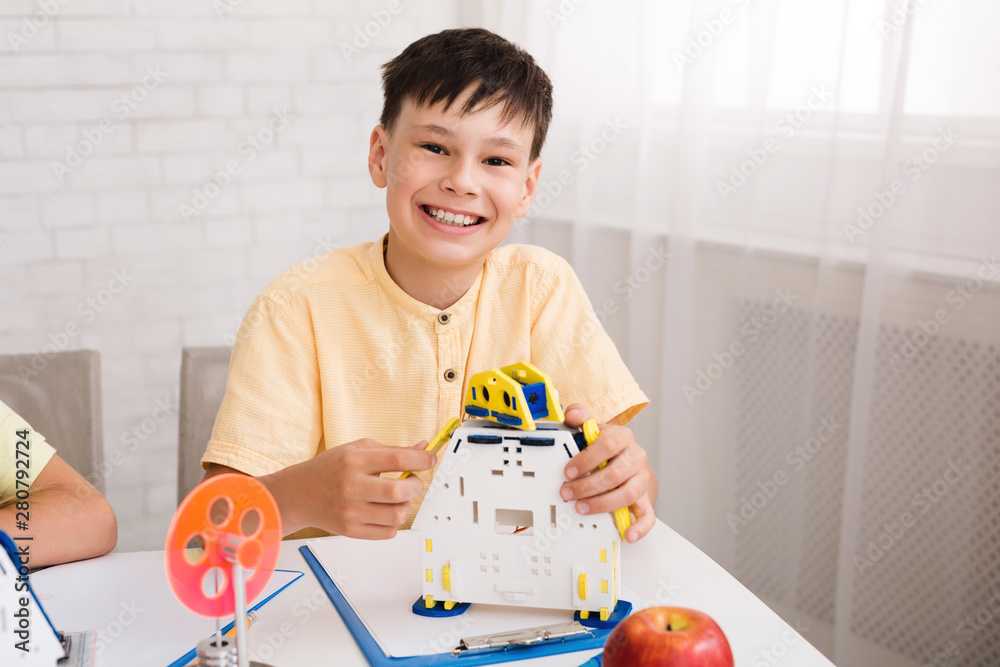 Poster Smart boy constructing robot and smiling to camera