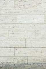 Fassade aus Travertin als Hintergrund mit kleinem Stück Boden aus Travertinstein