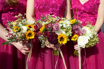 Three bridesmaids in lilac lace dresses with bouquets of fresh flowers, selective focus