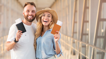 Happy couple smiling with flight tickets and passports at airport