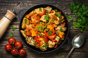 Chicken Stir fry with vegetables on wooden table.