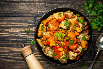 Chicken Stir fry with vegetables on wooden table.