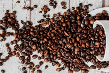 Black coffee in white cup and coffee beans on light wooden background. Top view, space for text