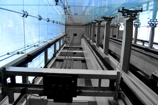 View Looking Up a Glass Elevator Shaft with Steel Posts and Glass Walls with Spider Fittings on the Outside of a Historic Building