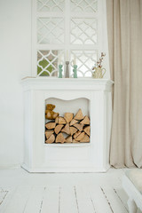 White stone fireplace with firewood without fire.
