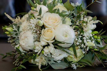 Bridal bouquet. The bride's bouquet. Beautiful bouquet of white, blue, pink flowers and greenery, decorated with long silk ribbon lies on a gray textural background