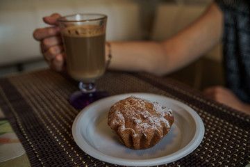 Hot coffee with delicious cupcake in a plate on the table in fast food cafe.