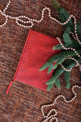 Holiday decoration with pearls, pearl beads, fir-tree branches and red book.