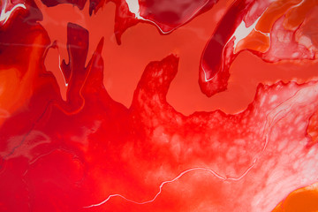Red abstract painting of acrylic colors, liquid texture