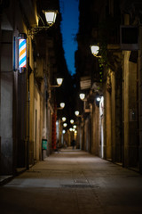 Fototapeta na wymiar Blurred downtown alley at night with barbershop or hairdresser's sign on the wall