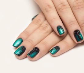Nails with green cat-eye nail polish and black chevron design