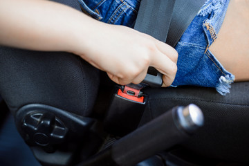 Closeup of woman fastening seat safety belt in car before departure