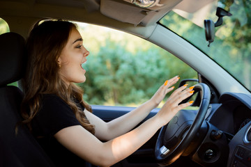 Naklejka premium Young girl driver sitting in the car with open mouth and crying before car crash. Concept of car crash and road accident