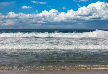 Sandy beach empty. Blue cloudy sky, blue sea with waves