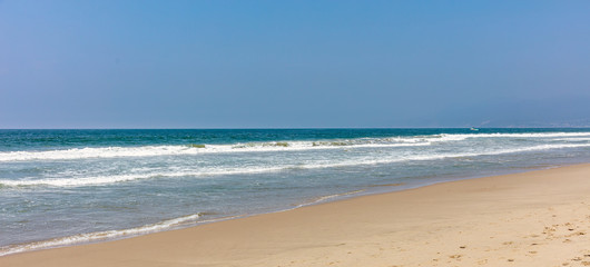 Sandy beach panoramic view. Blue clear sky, blue sea