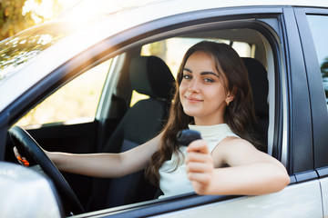 Happy woman driver brag about receiving driving license showing car key to the camera feeling happy...