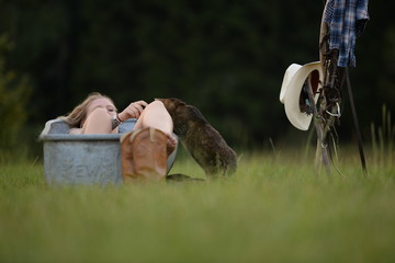 Badetag mit Katze. Junge Frau liegt im Freien in einer alten Wanne