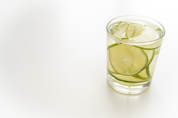 Close-up. A glass of a refreshing drink, a cocktail with sliced ​​lime on the right on the white table. Copy space. Side view