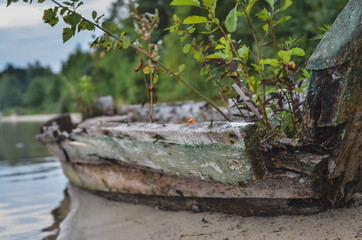 Old ruined fishing boat left on the lake shore. Selective focus