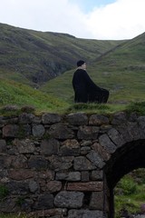Woman in black standing on an old bridge in Scotland