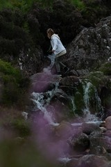 Naklejka na ściany i meble Woman walking in a stream in Scotland
