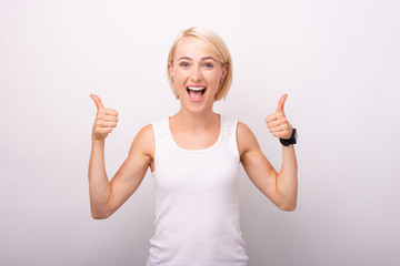 Portrait of amazed young happy woman showing thumbs up standing over white background