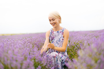 A young woman is smiling and looking at a scrub of lavender.