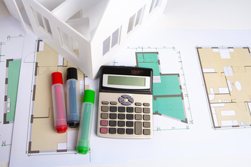 Fototapeta na wymiar Construction estimate. Calculation of the construction of the house. Calculator with drawings of the cottage are on the table. Construction Designer makes calculations. Layout of the future home.