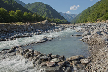 Fototapeta premium Mountain river valley landscape. Small lake made of riber stones within three months. Mountain river stream valley. River valley in mountains . stones a small river. Ismayilli Azerbaijan