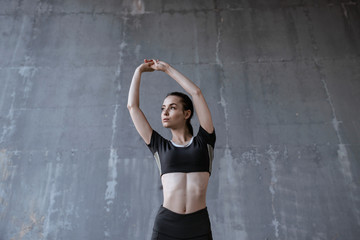 Sports woman on urban gray background. Fitness model working out outdoor. Beautiful slim brunette...