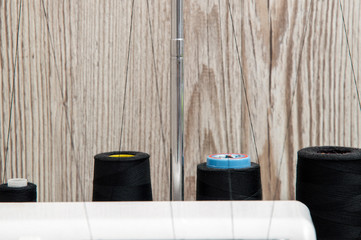 Close up. Details. Four black spools of thread mounted behind a sewing machine. Copy space.